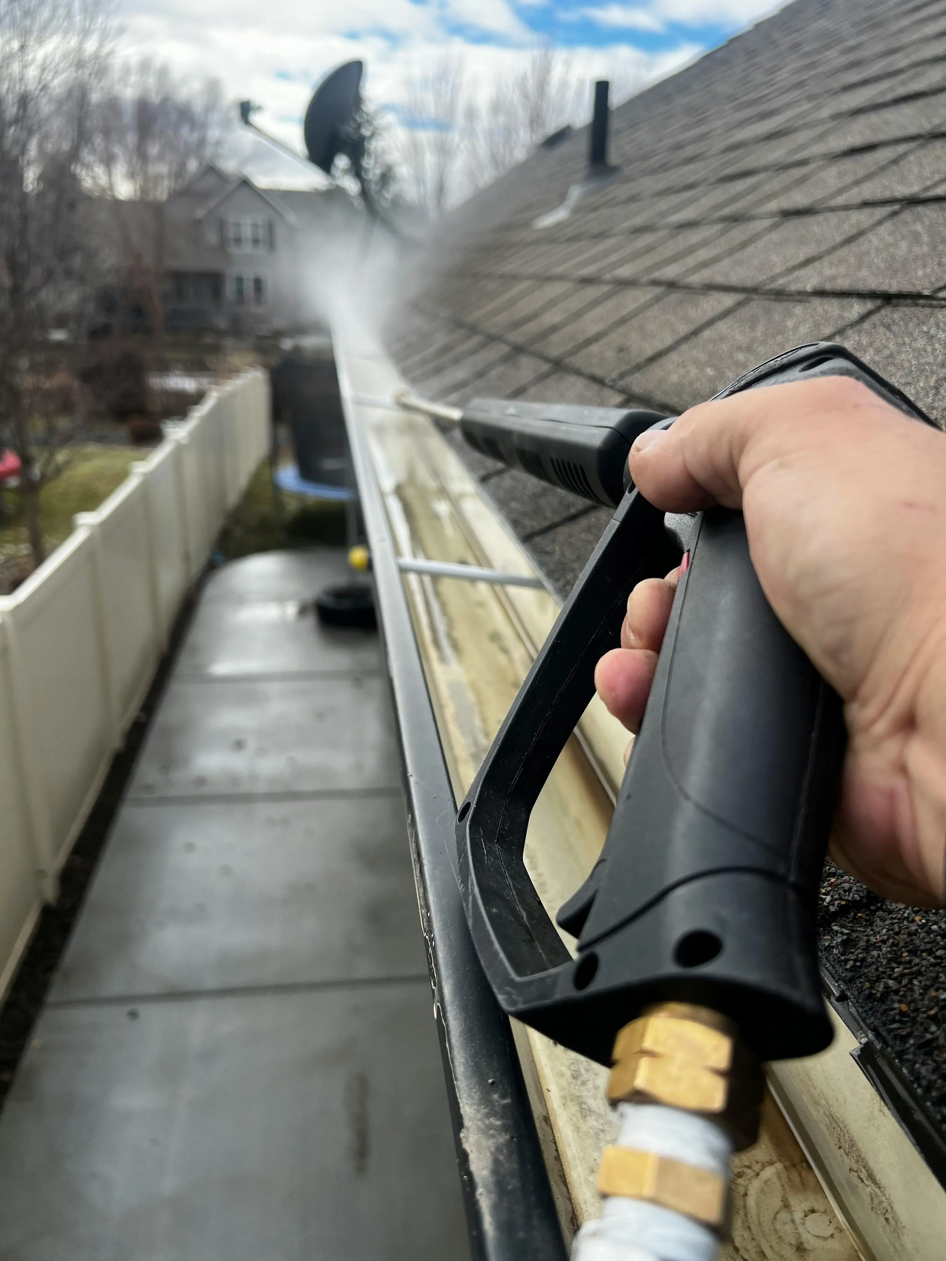 Professional roof technician in safety harness cleaning a Sydney home using soft wash technology